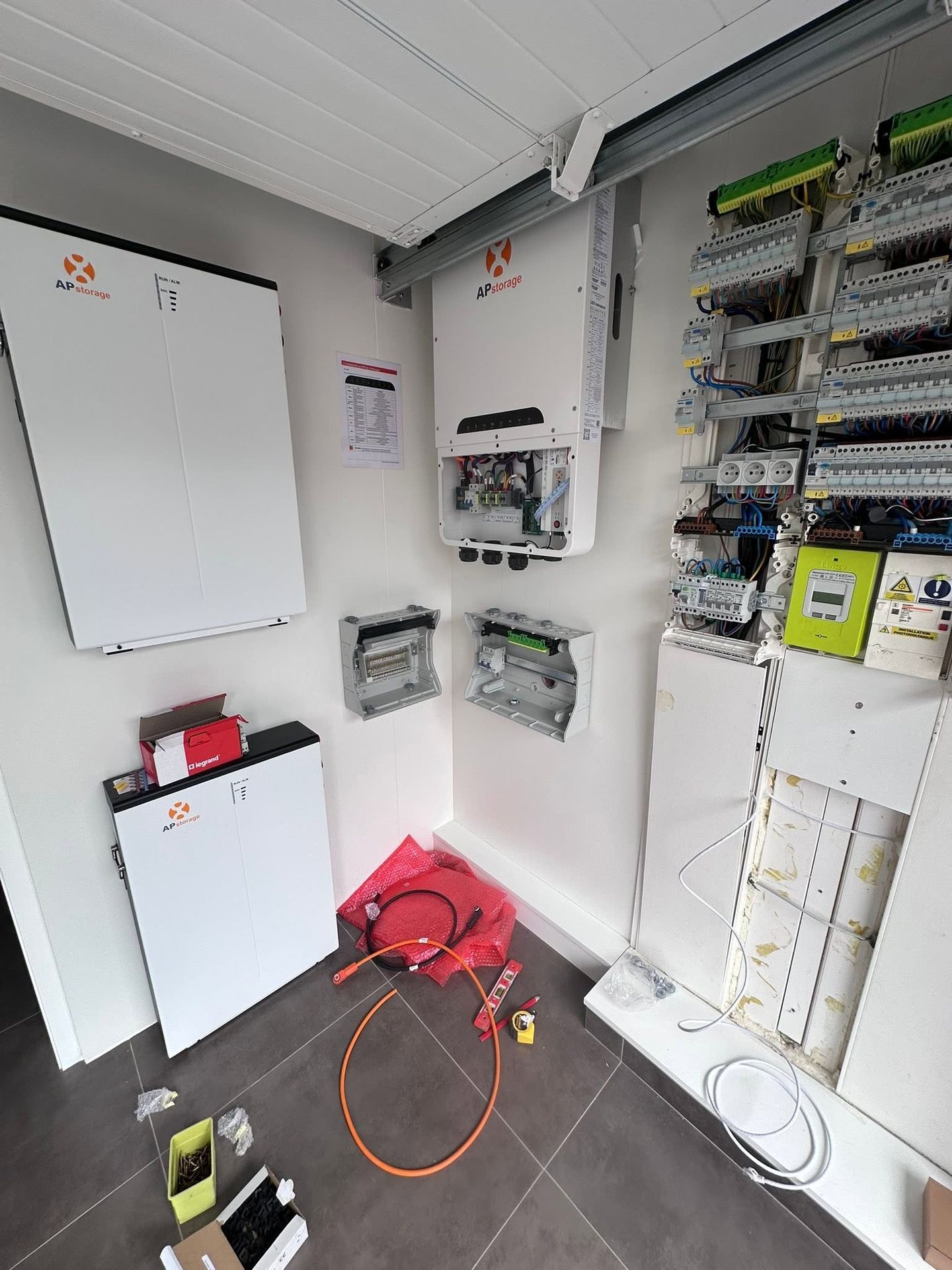 Système de stockage APsystems APstorage installé à côté du tableau électrique dans un local technique à Rumegies