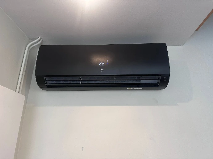 Unité intérieure noire d'une pompe à chaleur air/air Thermor installée dans un séjour à Wallers