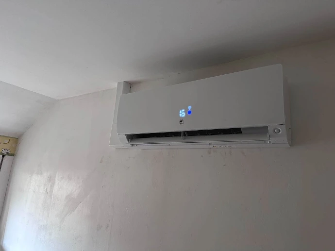 Unité intérieure de pompe à chaleur air/air Thermor installée dans un séjour sur un mur en béton ciré