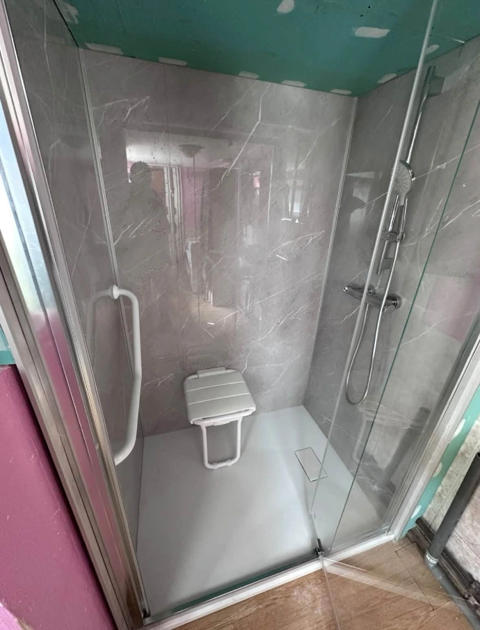 Siège de douche rabattable et barre de maintien installés dans la douche