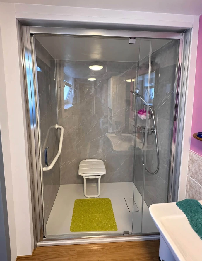 Paroi de douche avec porte battante et accès de plain-pied après rénovation